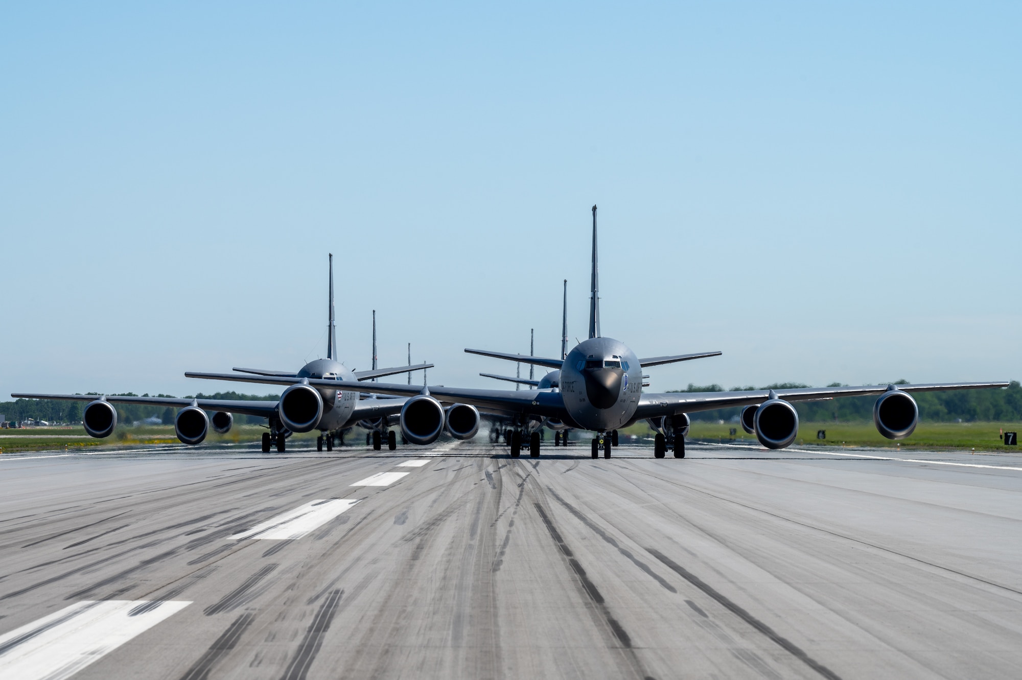The front-end view of a KC-135R Stratotanker formation on a runway. Eight tails are visible, with each staggered behind the other.