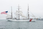 Coast Guard sails ship in foggy harbor.