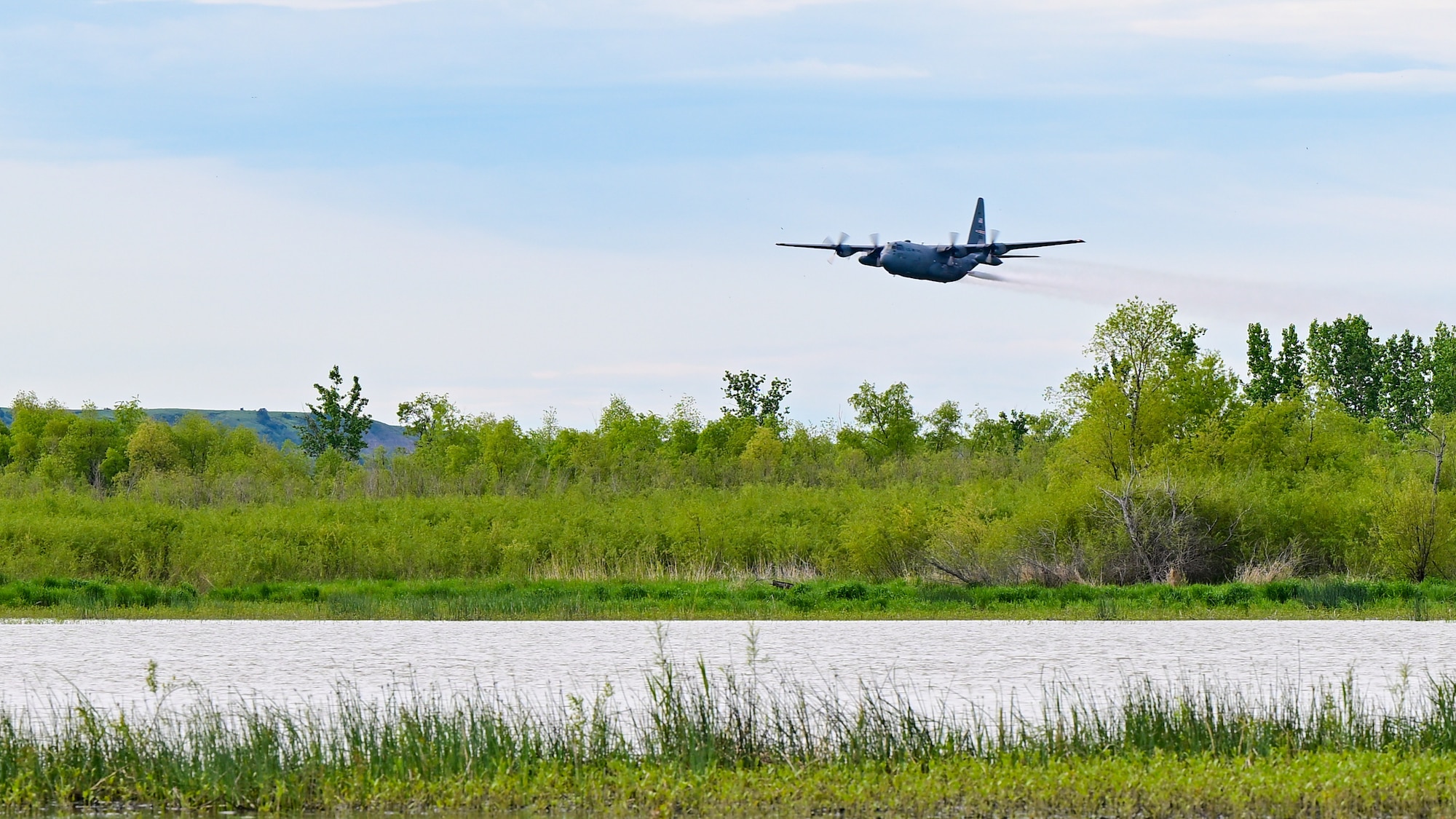 A 910th Airlift Wing aerial spray-modified C-130H Hercules aircraft disperses mosquito control product, June 3, 2024, over the flood banks of the Missouri River south of Williston, North Dakota.