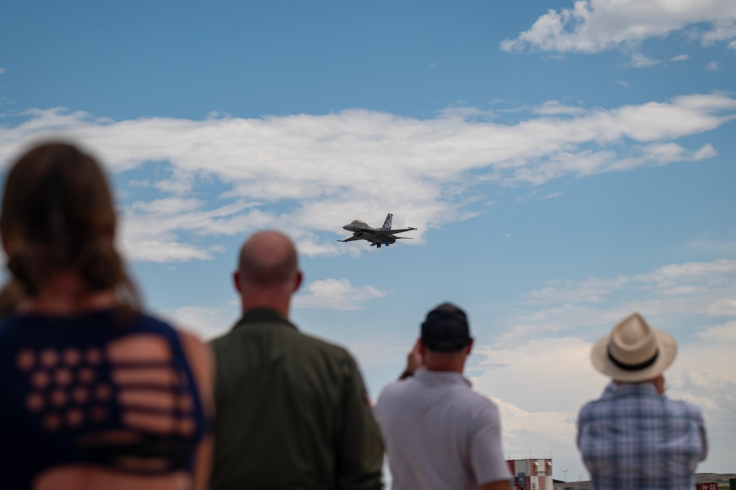 A U.S. Air Force F-16 Fighting Falcon aircraft flies over spectators.