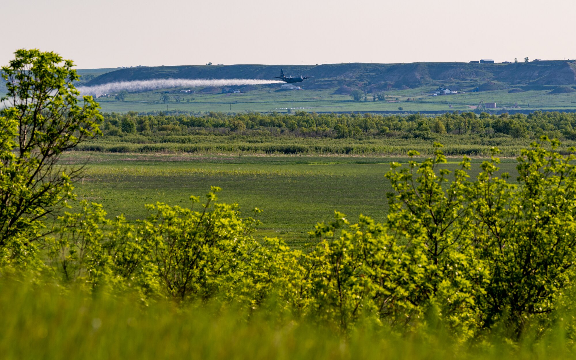 A 910th Airlift Wing aerial spray-modified C-130H Hercules aircraft disperses mosquito control product, May 31, 2024, over the flood banks of the Missouri River south of Williston, North Dakota.