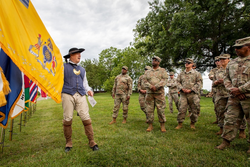 Soldiers of the 103rd Brigade Support Battalion listen to a member of the Sons of the American Revolution describe the different guidons used during the War of the American Revolution at Old Fort Harrods State Park in Harrodsburg, Kentucky on June 8, 2024. The 103rd BSB supported the 250th anniversary of the settlement of Harrodsburg by participating in posting the colors, marching in the parade, and providing a static display of military vehicles. (U.S. Army National Guard photo by Sgt. 1st Class Andrew Dickson)