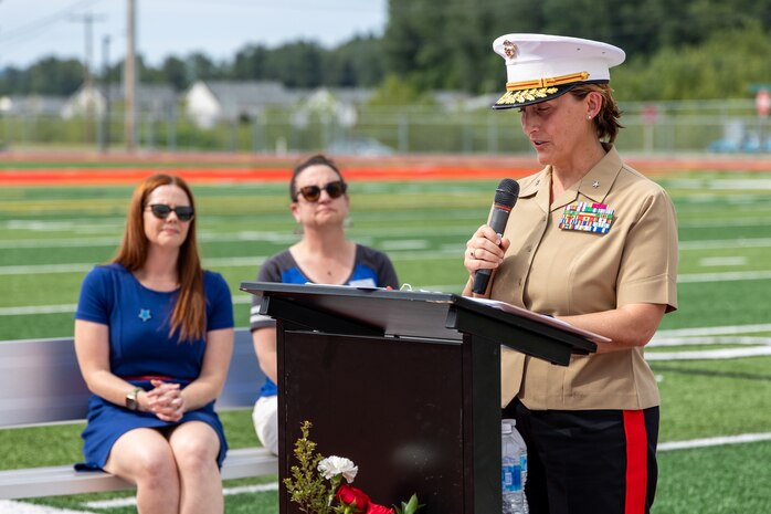 U.S. Marine Corps Brig. Gen. Valerie Jackson, commanding general of 4th Marine Logistics Group, gives remarks during an Honorary Marine ceremony for Arlan Russell at Orting Middle School in Orting, Wash., June 8, 2024. The title of Honorary Marine is an honor bestowed by the Commandant of the Marine Corps to civilians who have made extraordinary contributions to the Marine Corps. The program began in 1992 and is intended to strengthen the bond between the American people and the Marine Corps. Notable Honorary Marines include Chuck Norris, Gary Sinise, and Joe Rosenthal. Russell is the 109th person to earn the title of Honorary Marine. (U.S. Marine Corps photo by Staff Sgt. Courtney G. White)