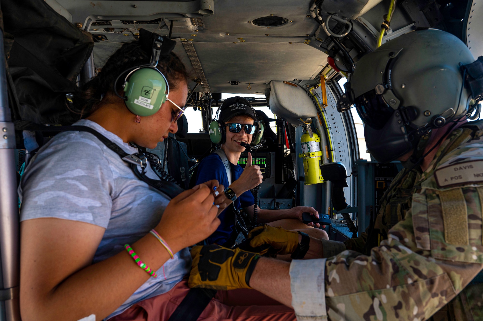 A man fastens the seatbelt for a student during a helicopter flight.