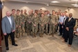 Photo of Several people pose for a photo in a conference room. The majority of those in the photo are wearing U.S. Army combat uniforms.