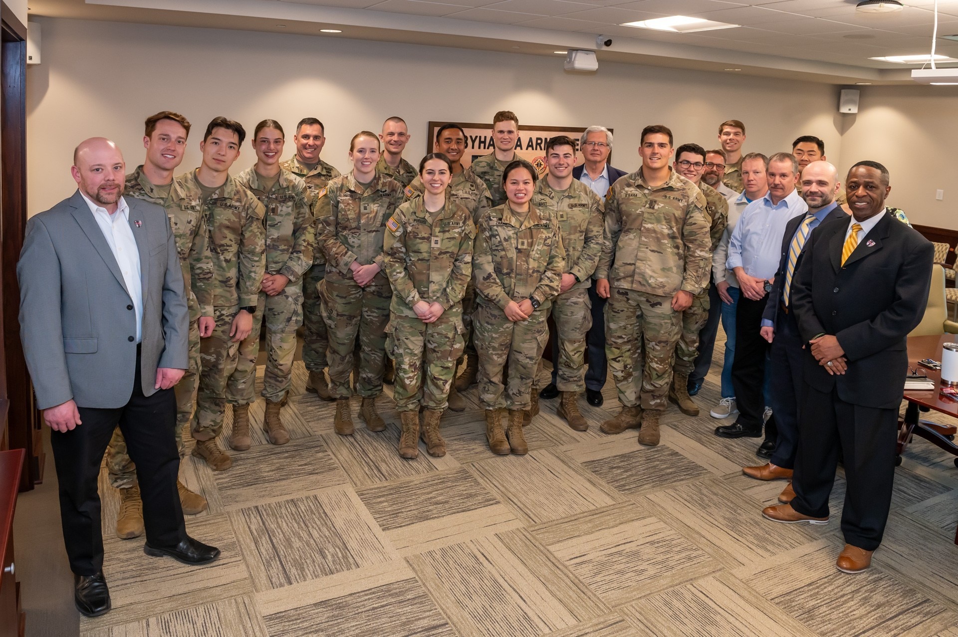 Photo of Several people pose for a photo in a conference room. The majority of those in the photo are wearing U.S. Army combat uniforms.