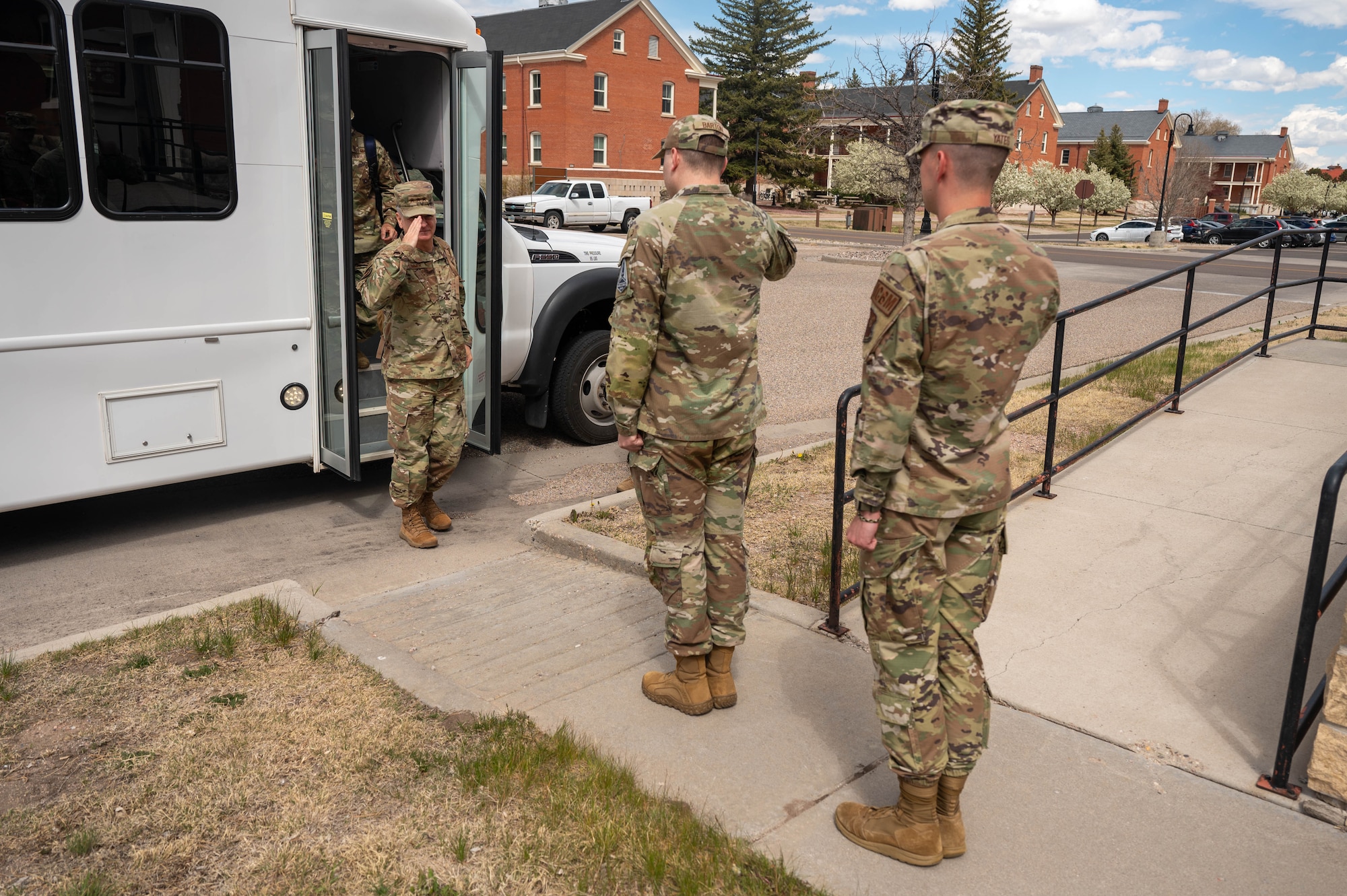service members saluting a general exiting a vehicle