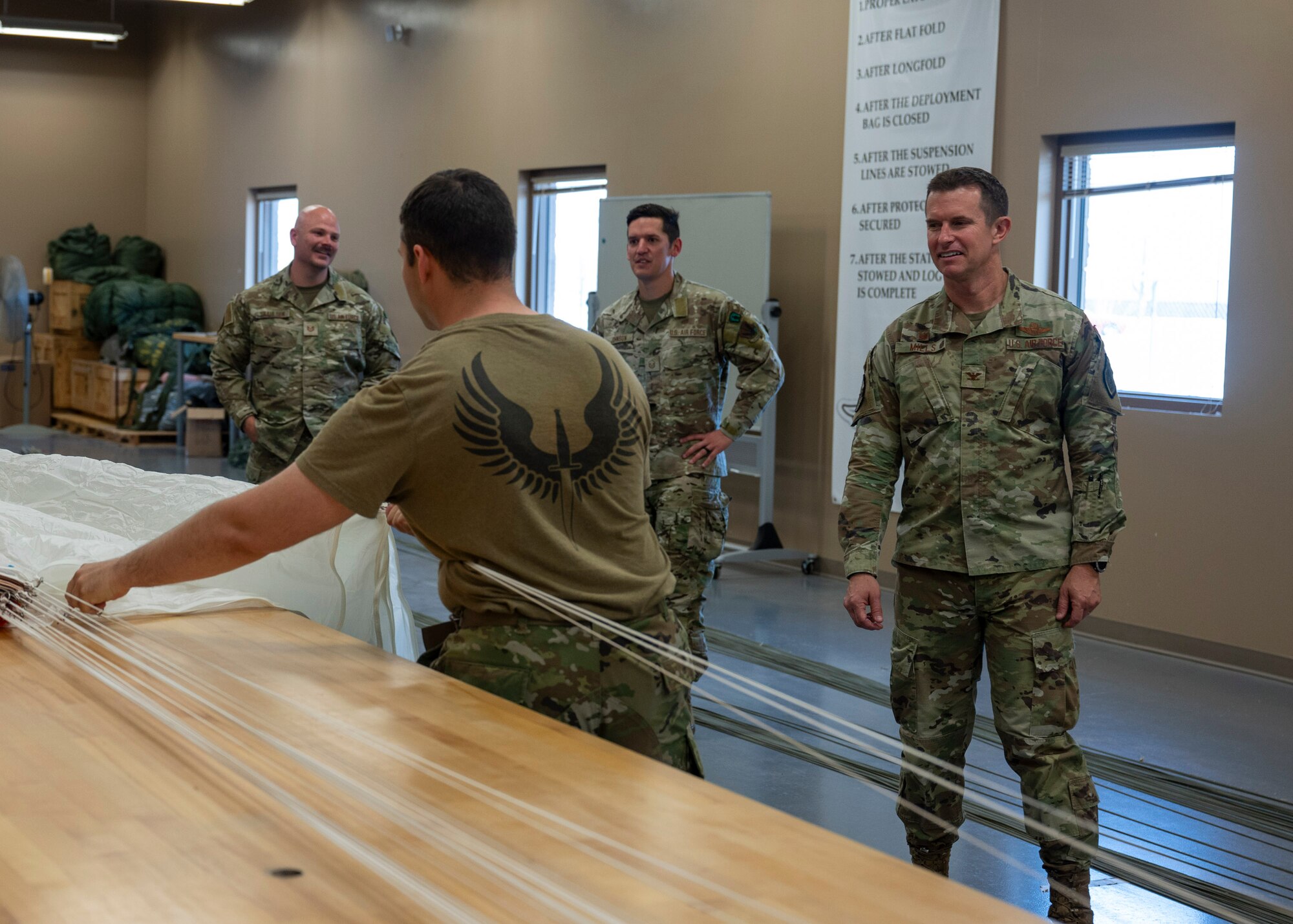 U.S. Air Force Airmen work together to pack a parachute at Davis-Monthan Air Force Base, Ariz., June 6, 2024. The Airmen hosted base leadership for the Airman for a Day program to enable  better understanding of the duties and responsibilities of Airmen across base. (U.S. Air Force photo by Airman 1st Class William Finn V)