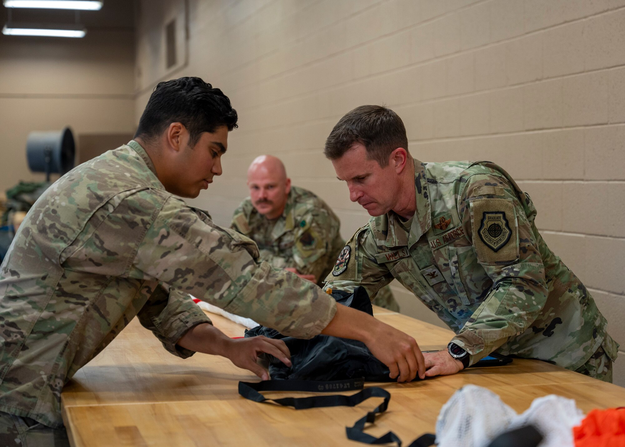 A U.S. Air Force Airman assigned to the 355th Operations Support Squadron demonstrates how to pack a parachute to Col. Scott Mills, 355th Wing commander, during the Airmen for a Day program at Davis-Monthan Air Force Base, Ariz., June 6, 2024. Mills participated in the program to learn more about the job duties that Airmen around base perform, get a chance to speak with them and to get to know them. (U.S. Air Force photo by Airman 1st Class William Finn V)