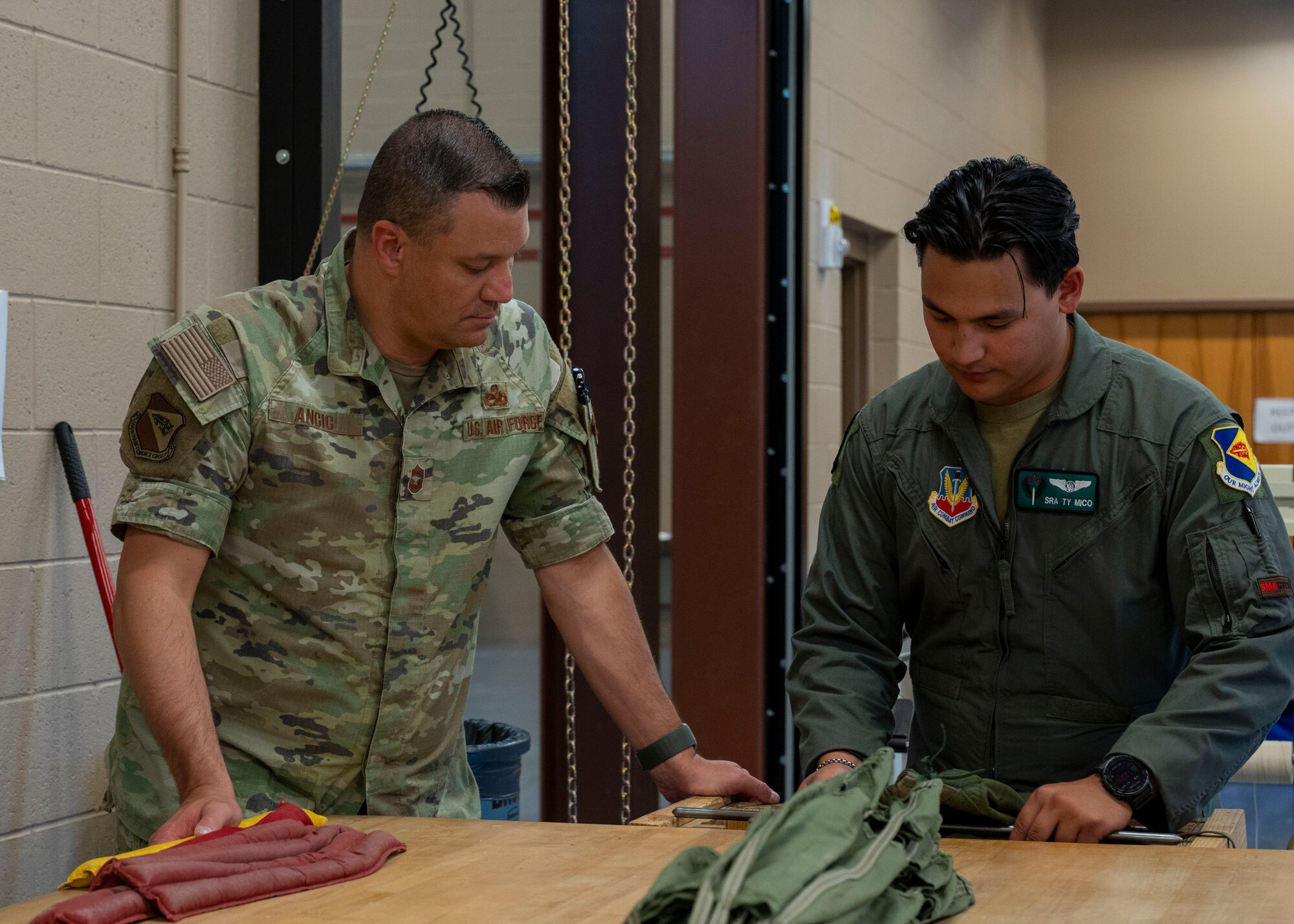 A U.S. Air Force Airman assigned to the 563rd Operations Support Squadron demonstrates how to pack a parachute to Chief Master Sgt. Andre Ancic, 355th Maintenance Group senior enlisted leader, during the Airman for a Day program at Davis-Monthan Air Force Base, Ariz., June 6, 2024. During Airman for a Day, base leadership spends time in a unit and learns about the job duties of the Airmen that work there. (U.S. Air Force photo by Airman 1st Class William Finn V)