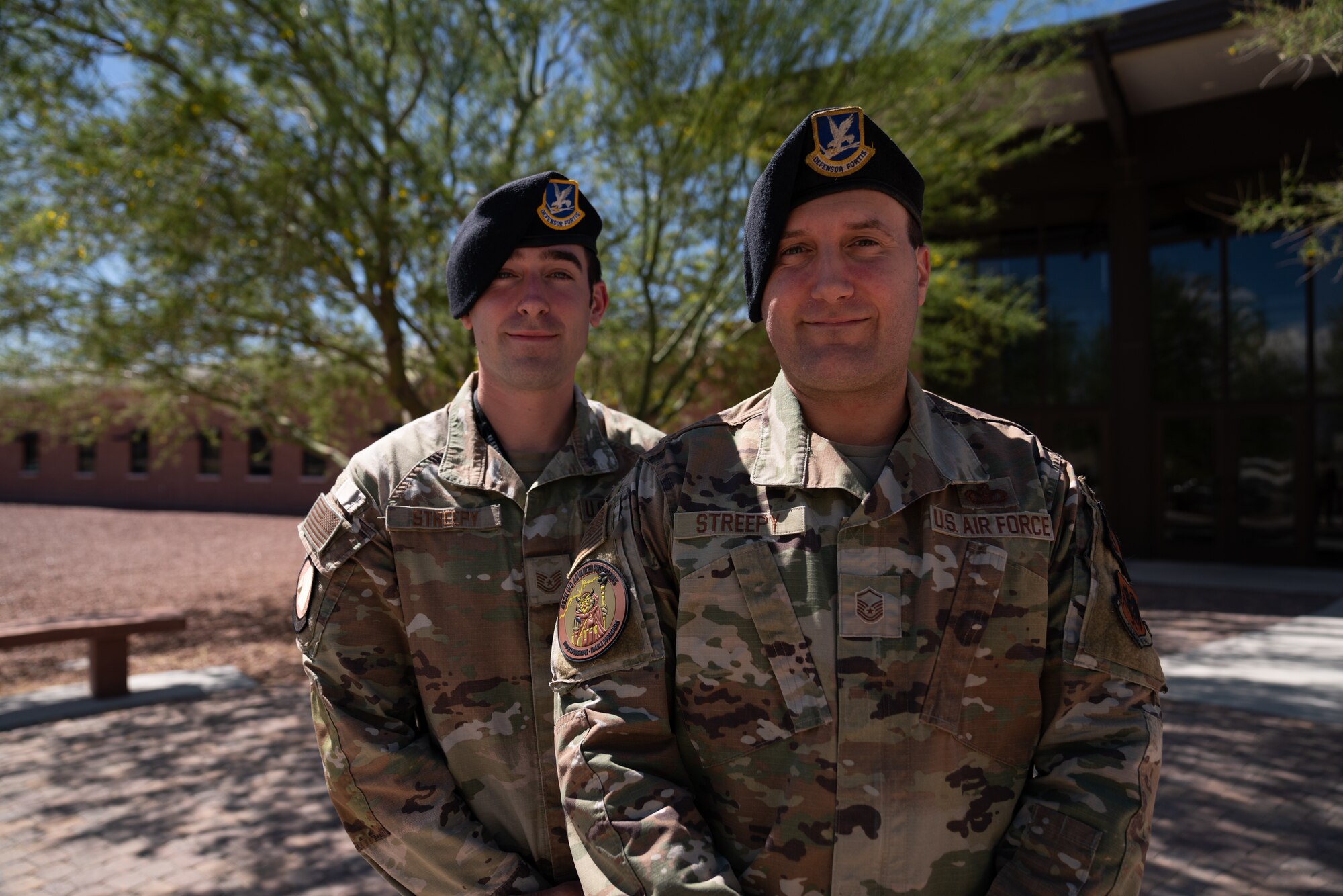 Two men in military uniforms smile for a portrait.