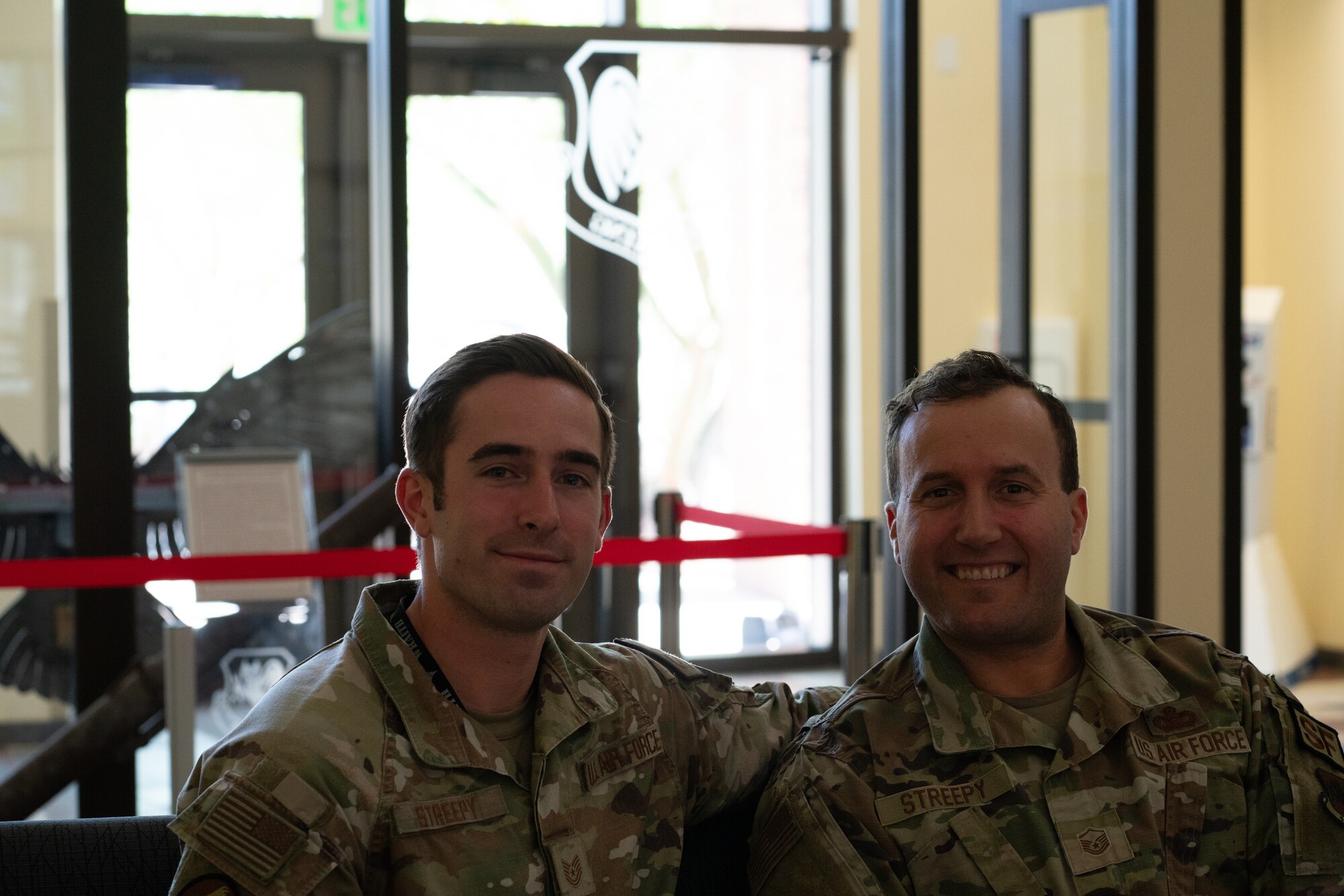 Two men in military uniforms smile for a portrait.