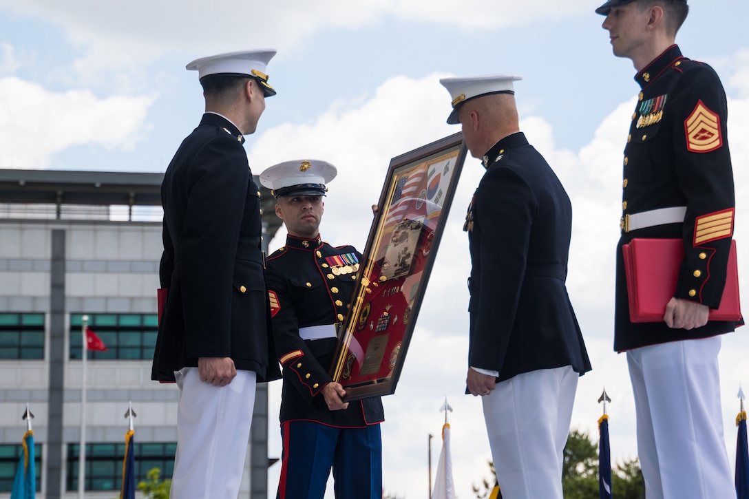 U.S. Marines with U.S. Marine Corps Forces, Korea present a gift to Lt. Col. Alexander Cole, left, an assistant chief of staff also with MARFORK, during a retirement ceremony on U.S. Army Garrison Humphreys, South Korea, May 28, 2024. MARFORK is the U.S. Marine Corps service component for United States Forces Korea and United Nations Command. MARFORK commands all U.S. Marine Forces assigned to USFK and UNC; as well as advises on the Marine Corps capabilities, support and proper employment of Marine Forces. (U.S. Marine Corps photo by Cpl. Dean Gurule)