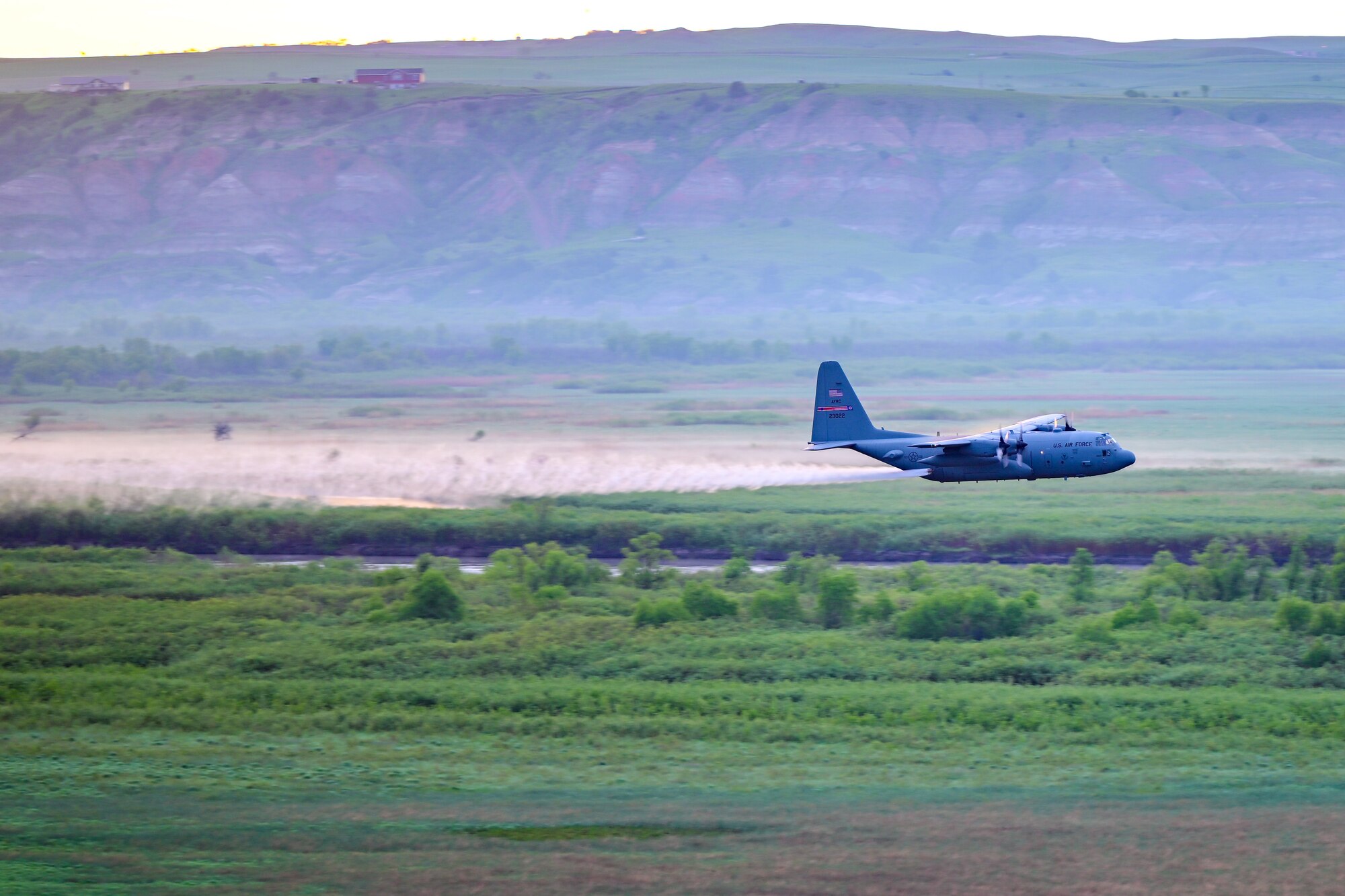 A 910th Airlift Wing aerial spray-modified C-130H Hercules aircraft disperses mosquito control product, June 3, 2024, over the flood banks of the Missouri River south of Williston, North Dakota.