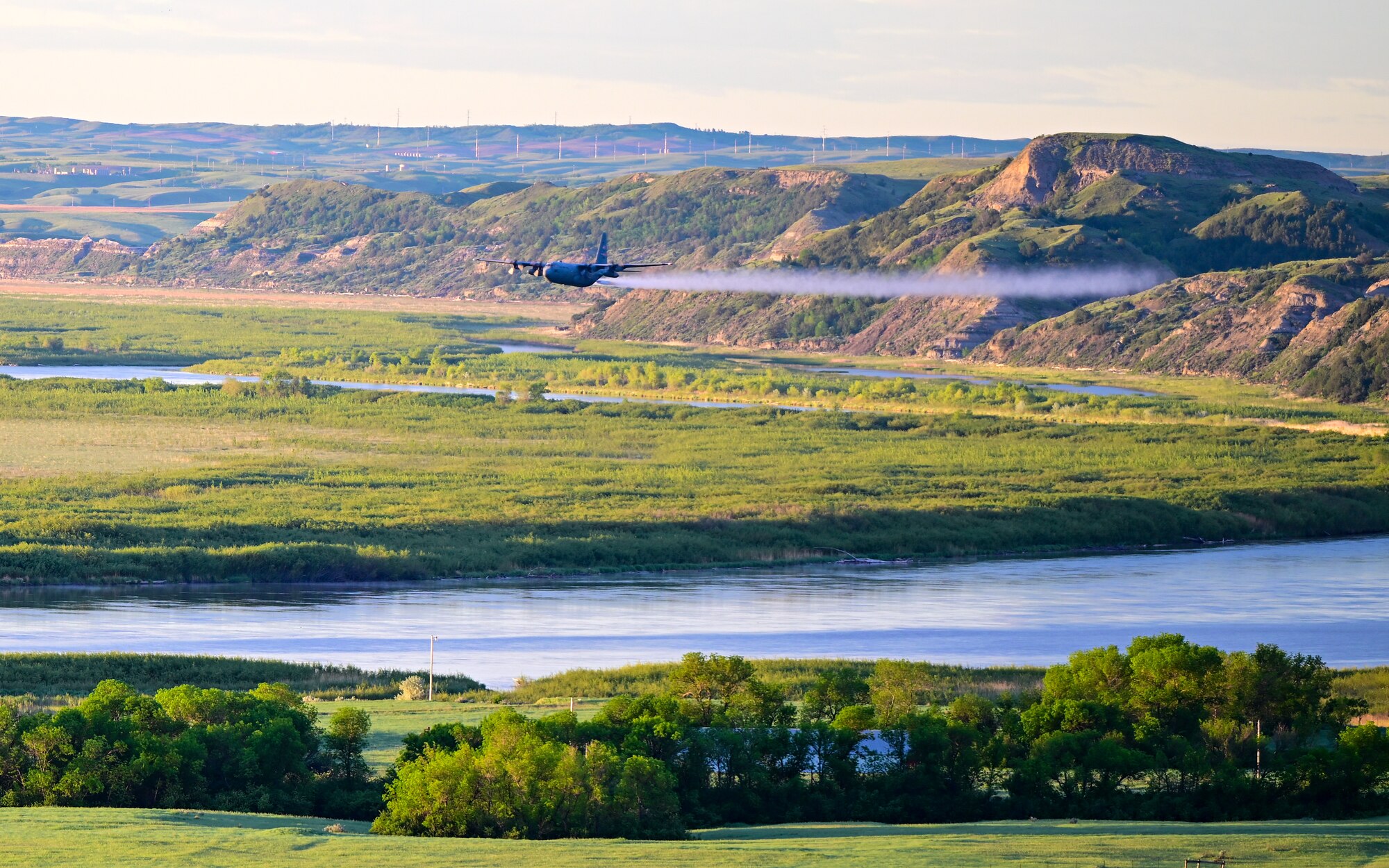 A 910th Airlift Wing aerial spray-modified C-130H Hercules aircraft disperses mosquito control product, June 3, 2024, over the flood banks of the Missouri River south of Williston, North Dakota.