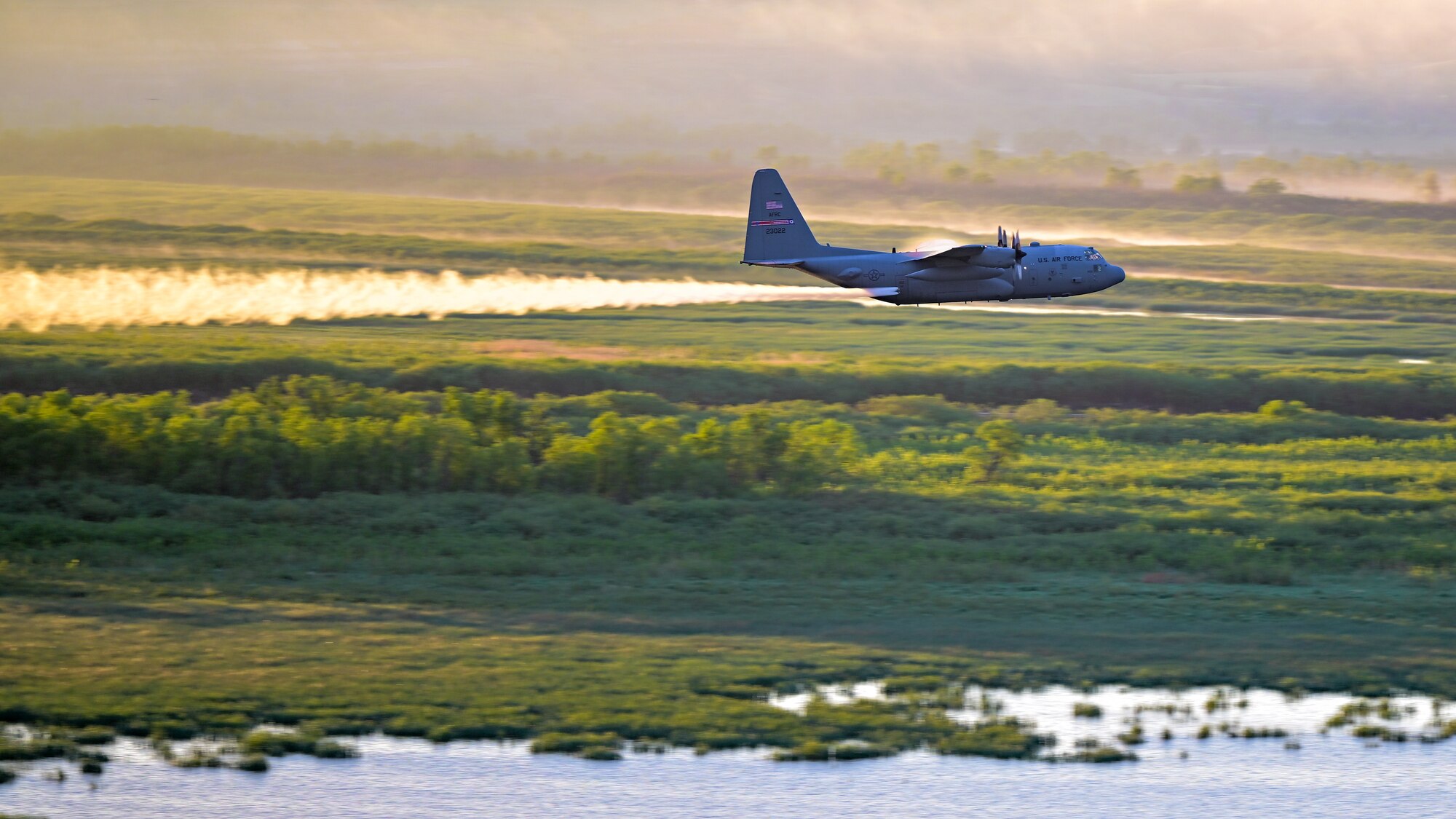 A 910th Airlift Wing aerial spray-modified C-130H Hercules aircraft disperses mosquito control product, June 3, 2024, over the flood banks of the Missouri River south of Williston, North Dakota.