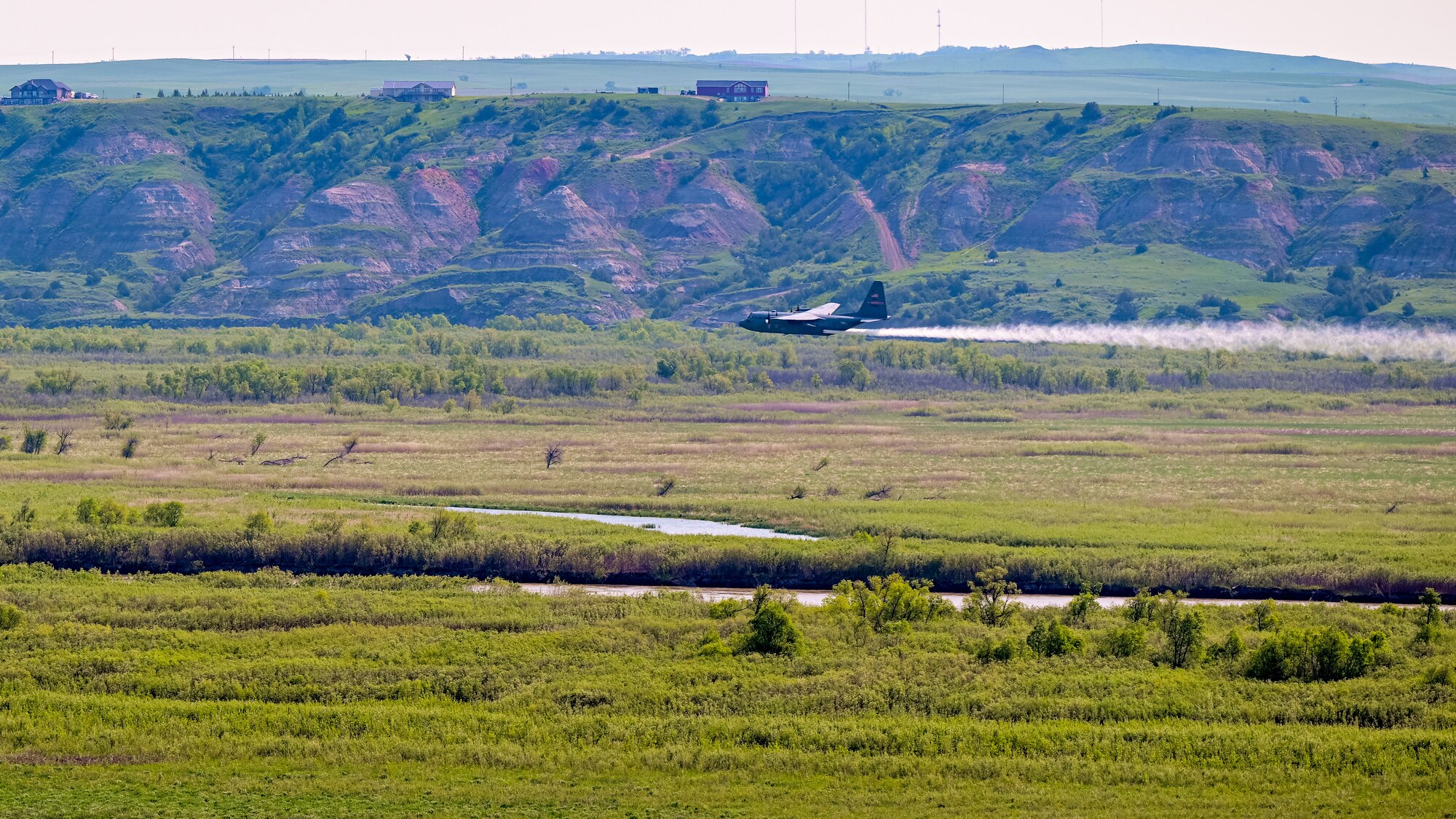 A 910th Airlift Wing aerial spray-modified C-130H Hercules aircraft disperses mosquito control product, May 31, 2024, over the flood banks of the Missouri River south of Williston, North Dakota.