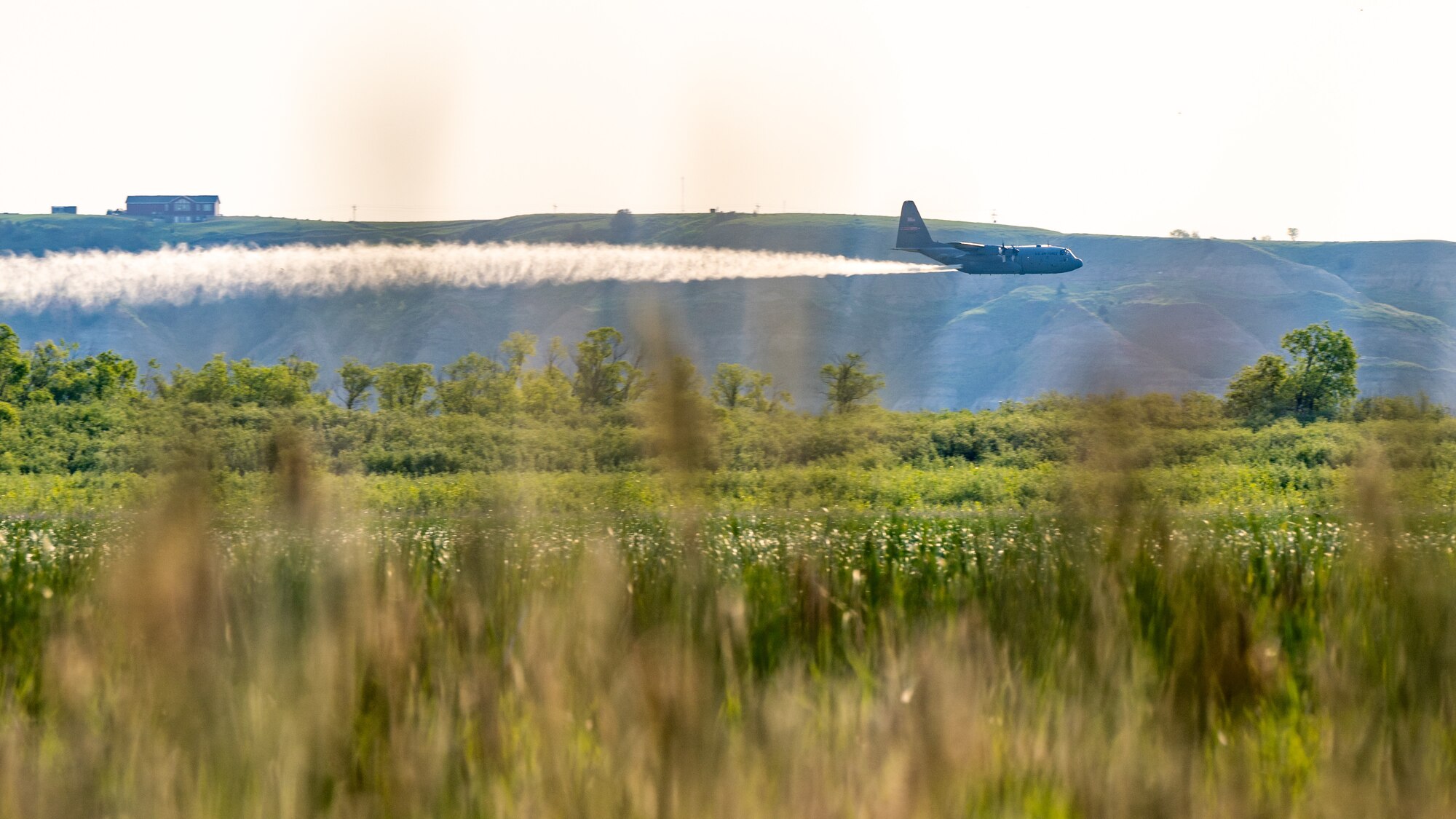 A 910th Airlift Wing aerial spray-modified C-130H Hercules aircraft disperses mosquito control product, May 31, 2024, over the flood banks of the Missouri River south of Williston, North Dakota.