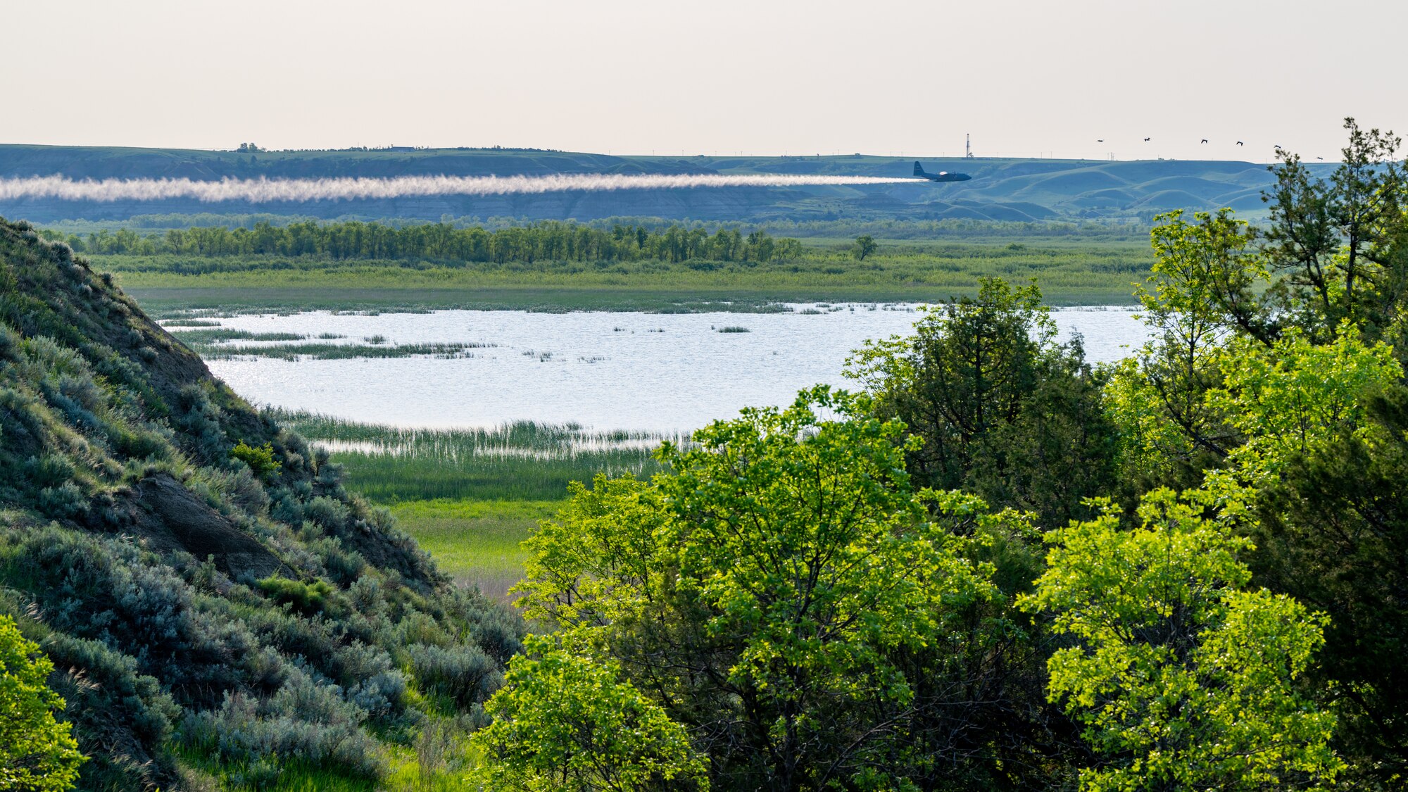 A 910th Airlift Wing aerial spray-modified C-130H Hercules aircraft disperses mosquito control product, May 31, 2024, over the flood banks of the Missouri River south of Williston, North Dakota.