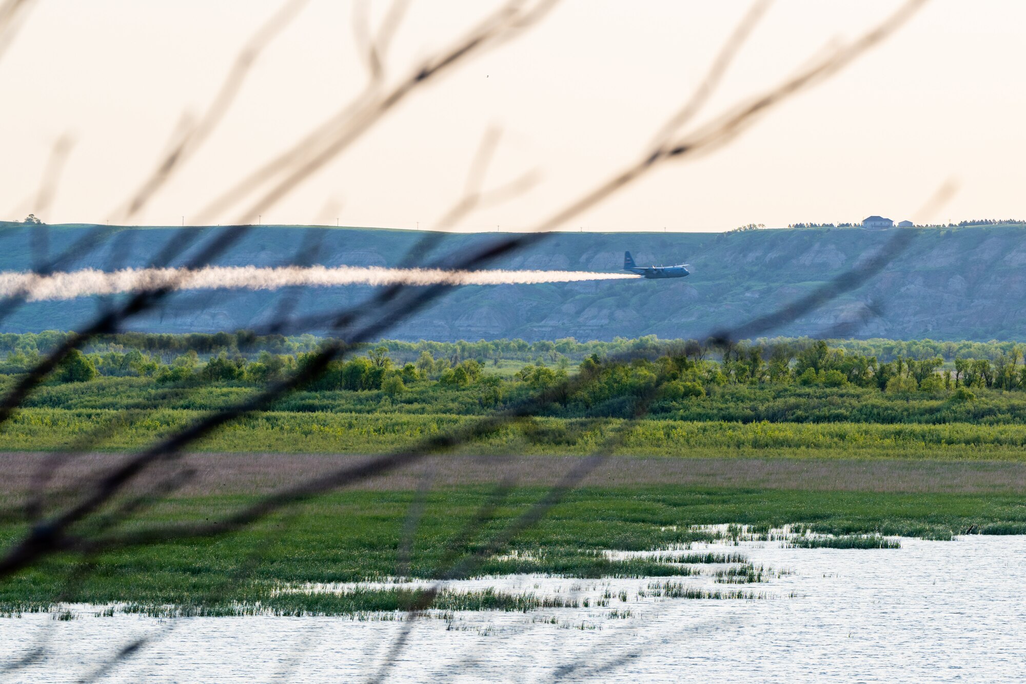 A 910th Airlift Wing aerial spray-modified C-130H Hercules aircraft disperses mosquito control product, May 31, 2024, over the flood banks of the Missouri River south of Williston, North Dakota.