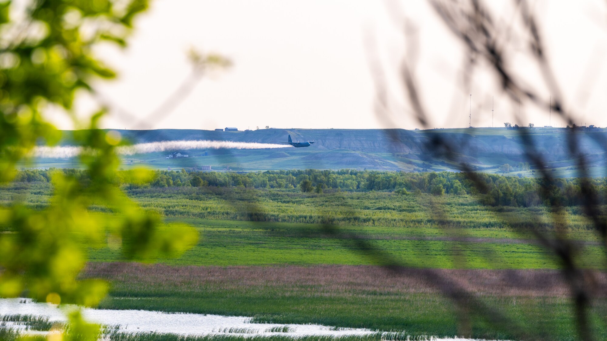 A 910th Airlift Wing aerial spray-modified C-130H Hercules aircraft disperses mosquito control product, May 31, 2024, over the flood banks of the Missouri River south of Williston, North Dakota.