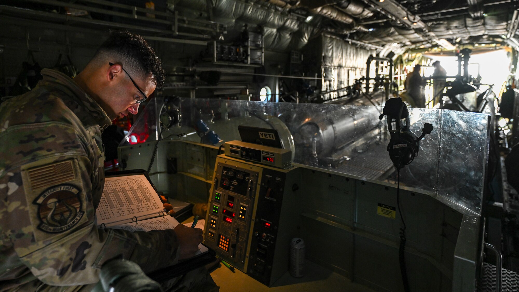U.S. Air Force Staff Sgt. Bryce Cooper, an aerial spray system maintainer with the 910th Aerial Spray Maintenance Flight, denotes the product load, May 29, 2024, while his colleagues fill the tanks of a 910th Airlift Wing Modular Aerial Spray System onboard an aerial spray modified C-130H Hercules aircraft parked at Williston Basin International Airport, North Dakota.