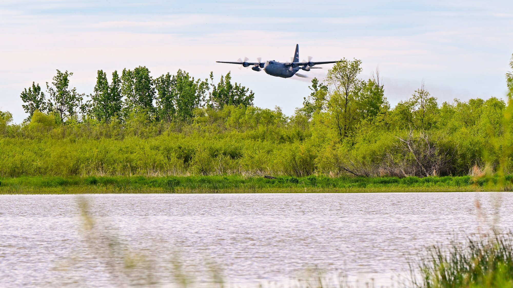 A 910th Airlift Wing aerial spray-modified C-130H Hercules aircraft disperses mosquito control product, June 3, 2024, over the flood banks of the Missouri River south of Williston, North Dakota.
