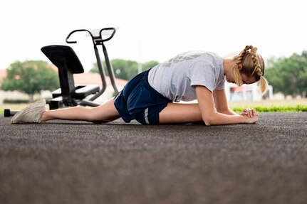 woman stretches outside in Air Force athletic clothes