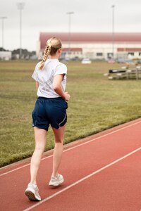 woman runs around the track wearing Air Force athletic clothes