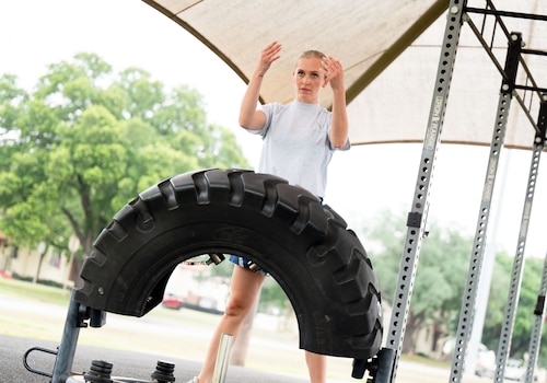 woman flips a tire outside under the bright sun