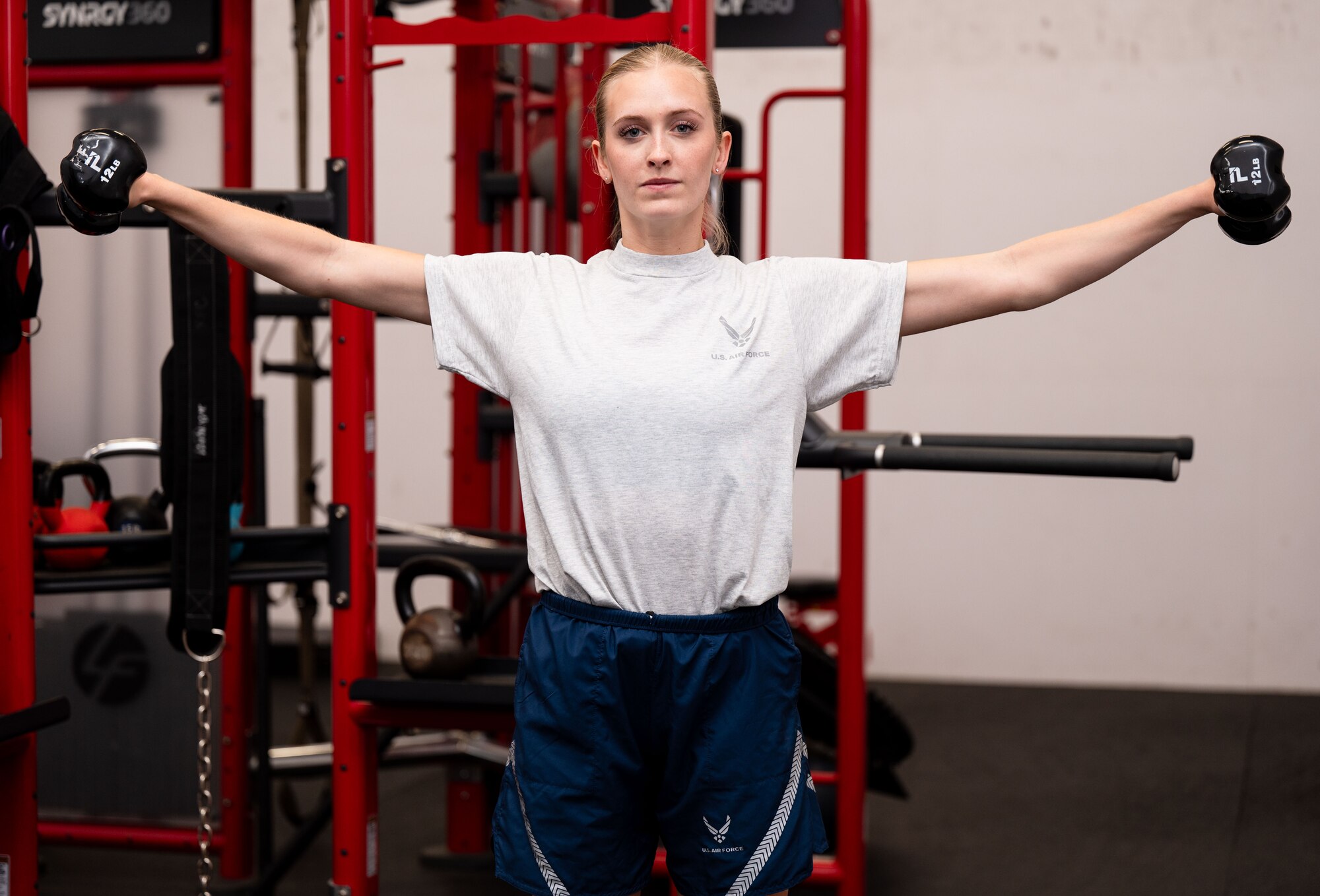 woman lifts weights at her side in the gym