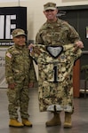 Jamir Gibbs,7, of Marion, Illinois, shows off the football jersey he received with 1st Sgt. Beau Detrick of November Company, Recruit Sustainment Program, Illinois Army National Guard Recruiting and Retention Command. Jamir was promoted to 