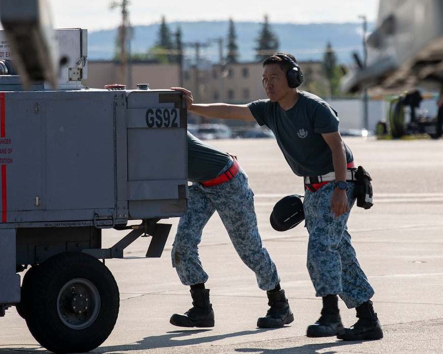 Two members from the Republic of Singapore Air Force push a maintenance cart.