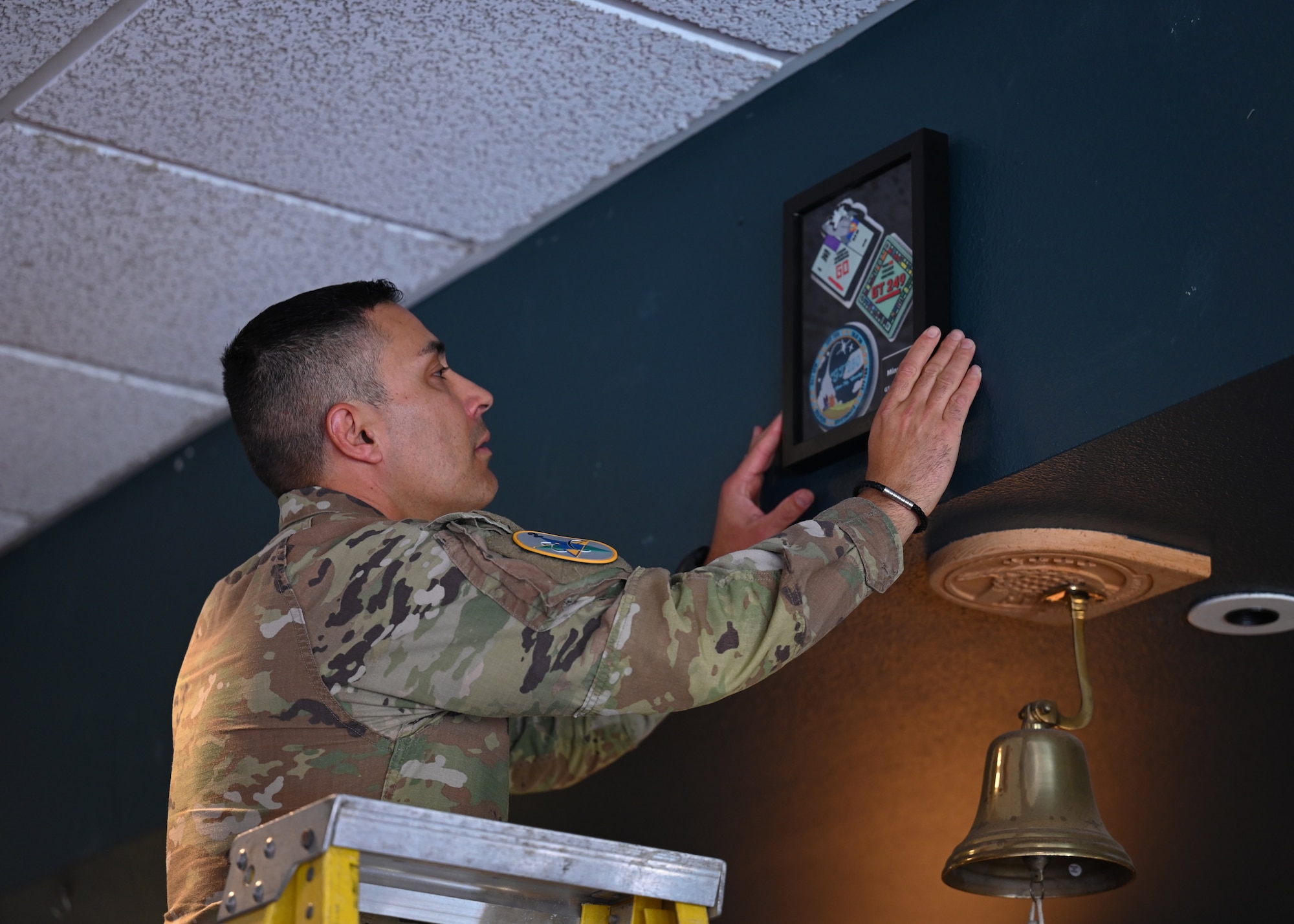 A man hangs up a frame on a wall.