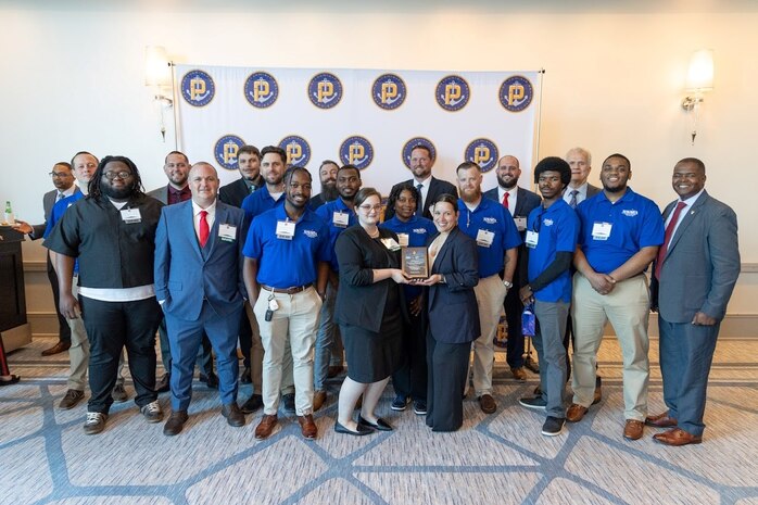 The U.S. Navy's Submarine Industrial Base (SIB) program hosts a Talent Pipeline Project (TPP) Signing Day event at Hilton Philadelphia at Penn’s Landing in Philadelphia on May 23, 2024. The ceremony recognized the latest wave of skilled workers joining the Defense Industrial Base (DIB) and first cohort to enter the U.S. Navy as civilian employees at Naval Surface Warfare Center, Philadelphia Division (NSWCPD). Gathered on stage: NSWCPD trainers, mentors and supervisors along withTechnical Director Nigel C. Thijs, SES; and NSWCPD’s one-year anniversary program participants and new hires, including: Stefan Schein, Yolanda Butler, Tahir Abdul-Hadi, Patrick Cosgrove, Wayne Fuller, Rassunako Person, Andrew Butler, Justin Holmes, Mark Byrd Jr., Ryan Crabill, Brandon Muir, and Ranoldo Turcious Acosto (all from the West Philadelphia Skills Initiative). In front holding the plaque: NSWCPD’s Stephanie Thomas (left) and Victoria Gonzalez (right). (Courtesy Photo)