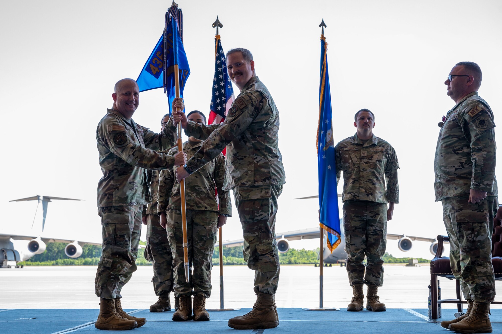 U.S. Air Force Col. Bary Flack, left, 436th Mission Generation Group commander, passes the guidon to Maj. Joshua Belanger, incoming 436th Maintenance Squadron commander, during a change of command ceremony at Dover Air Force Base, Delaware, June 10, 2024. The ceremony saw Lt. Col. Alexander Barnett, outgoing 436th MXS commander, relinquish command to Belanger. (U.S. Air Force photo by Senior Airman Amanda Jett)
