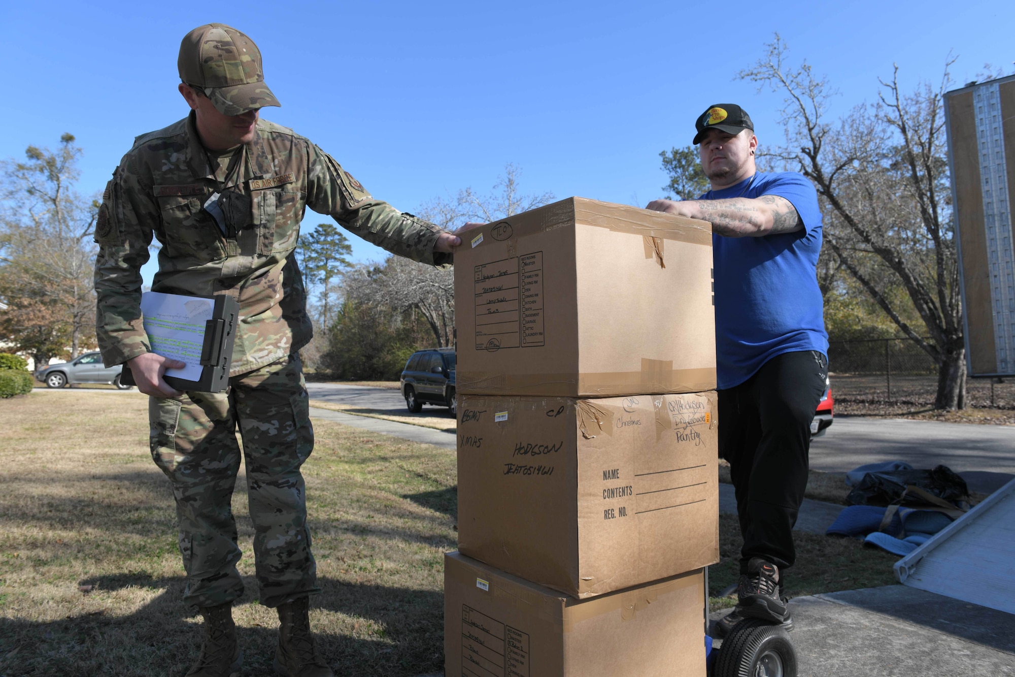 An airman in uniform inspects a stack of boxes.
