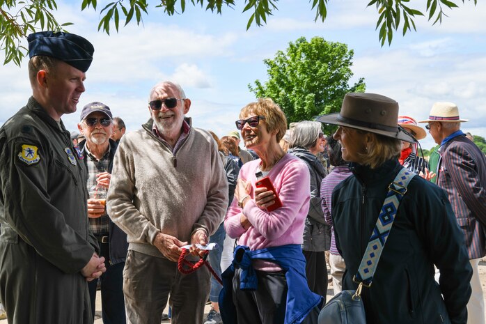 U.S. Air Force Lt. Col. Brad Fisher, commander of the 15th Airlift Squadron, talks with attendees at the RAF Ramsbury Community Fair, June 8, 2024, in Ramsbury, U.K. The event commemorated the 80th anniversary of D-Day, bringing together community members and visitors to honor the historical legacy of the 437th Troop Carrier Group. (U.S. Air Force photo by 1st Lt. Taylor Ferry)