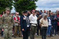 U.S. Air Force Maj. David Martin, commander of the 437th Aerial Port Squadron, stands at attention with event organizers during a moment of silence at the RAF Ramsbury Community Fair, June 8, 2024, in Ramsbury, U.K. The ceremony marked the 80th anniversary of D-Day, honoring the sacrifices and contributions of those who served. (U.S. Air Force photo by 1st Lt. Taylor Ferry)