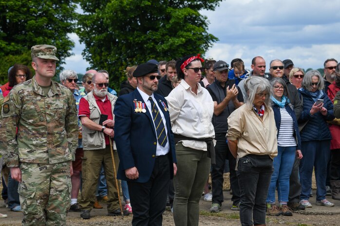 U.S. Air Force Maj. David Martin, commander of the 437th Aerial Port Squadron, stands at attention with event organizers during a moment of silence at the RAF Ramsbury Community Fair, June 8, 2024, in Ramsbury, U.K. The ceremony marked the 80th anniversary of D-Day, honoring the sacrifices and contributions of those who served. (U.S. Air Force photo by 1st Lt. Taylor Ferry)