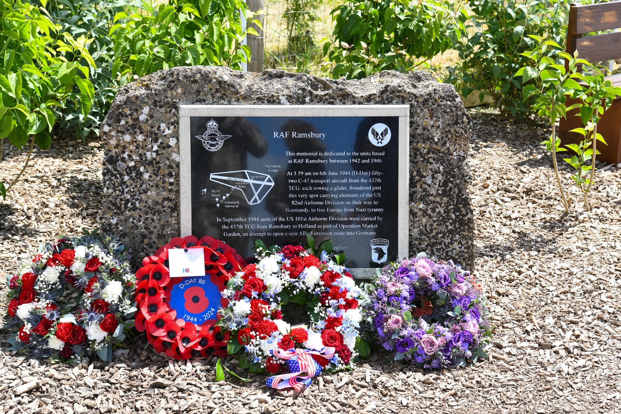 The memorial dedicated to the 437th Troop Carrier Group at RAF Ramsbury, adorned with wreaths laid during the RAF Ramsbury Community Fair, June 8, 2024, in Ramsbury, U.K. The memorial honors the units based at RAF Ramsbury from 1942 to 1946 and their significant contributions during D-Day and throughout World War II. (U.S. Air Force photo by 1st Lt. Taylor Ferry)