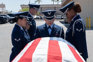 A group of Airmen stand in front of a casket.