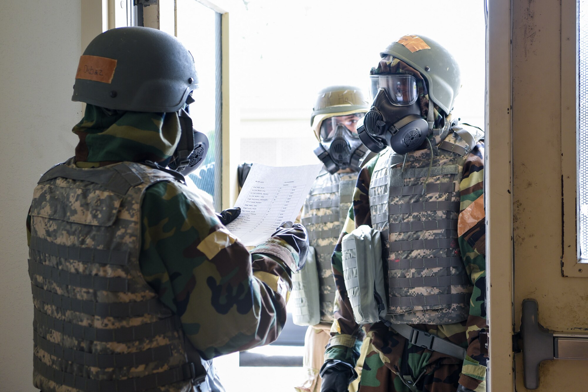 One Airman checks two other Airmen's identities before allowing entry into the building.