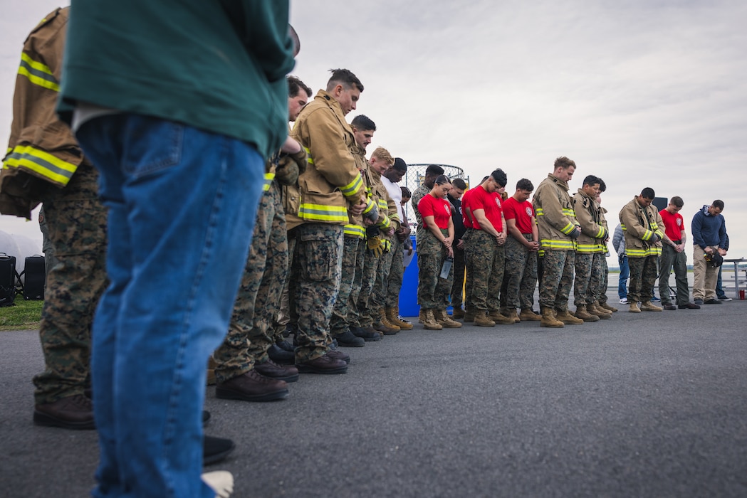 U.S. Marines with Marine Corps Air Facility Quantico, Marine Corps Air Station New River, Marine Corps Air Station Cherry Point and Marine Corps Air Station Beaufort, bow their heads in prayer during the Aircraft Rescue and Fire Fighter Rodeo competition on Marine Corps Base Quantico, Virginia, April 15, 2024. The ARFF Rodeo is a competition for Marines to showcase their operational knowledge of firefighting tactics, techniques, and procedures. (U.S. Marine Corps Photo by Lance Cpl. Joaquin Dela Torre)