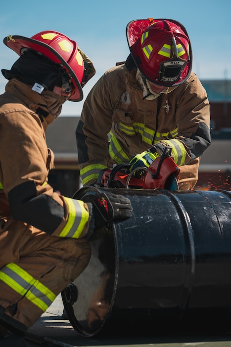 U.S. Marines with Marine Corps Air Facility Quantico, cut through barrels during the Aircraft Rescue and Fire Fighter Rodeo competition on Marine Corps Base Quantico, Virginia, April 15, 2024. The ARFF Rodeo is a competition for Marines to showcase their operational knowledge of firefighting tactics, techniques, and procedures. (U.S. Marine Corps Photo by Lance Cpl. Joaquin Dela Torre)