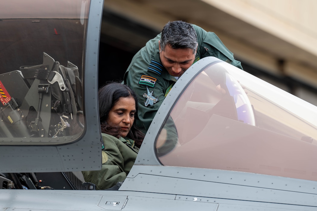 Sripriya Ranganathan, Charge d’Affaires of India to the United States sits in the cockpit of a Indian Air Force Rafale while an Indian Air Force member points out controls.