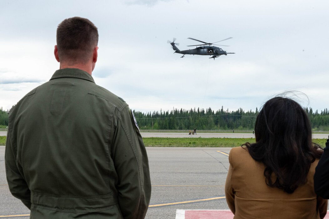 U.S. Air Force Col. Paul Townsend (left), 354th Fighter Wing commander, and Sripriya Ranganathan, Charge d’Affaires of India to the United States, stand next to each other and watch a helicopter fly.