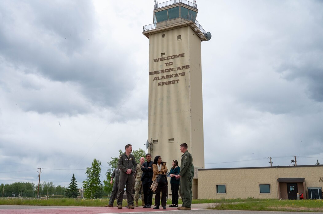 A group of people stand in front of the air traffic control tower.