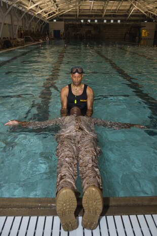 U.S. Marine Corps Gunnery Sgt. Josiah Sandel, a Marine Corps Instructor of Water Survival, assists Recruit Joshua Haruna with Hotel Company, 2nd Recruit Training Battalion, during a water survival training class at Marine Corps Recruit Depot San Diego, California, June 4, 2024. Recruits are taught basic water survival prior to conducting their basic swim qualification. Basic swim qualification consists of a 25-meter swim, tower jump into the water, four-minute tread, 25-meter pack swim, and an underwater gear shed. (U.S. Marine Corps photo by Lance Cpl. Janell B. Alvarez)