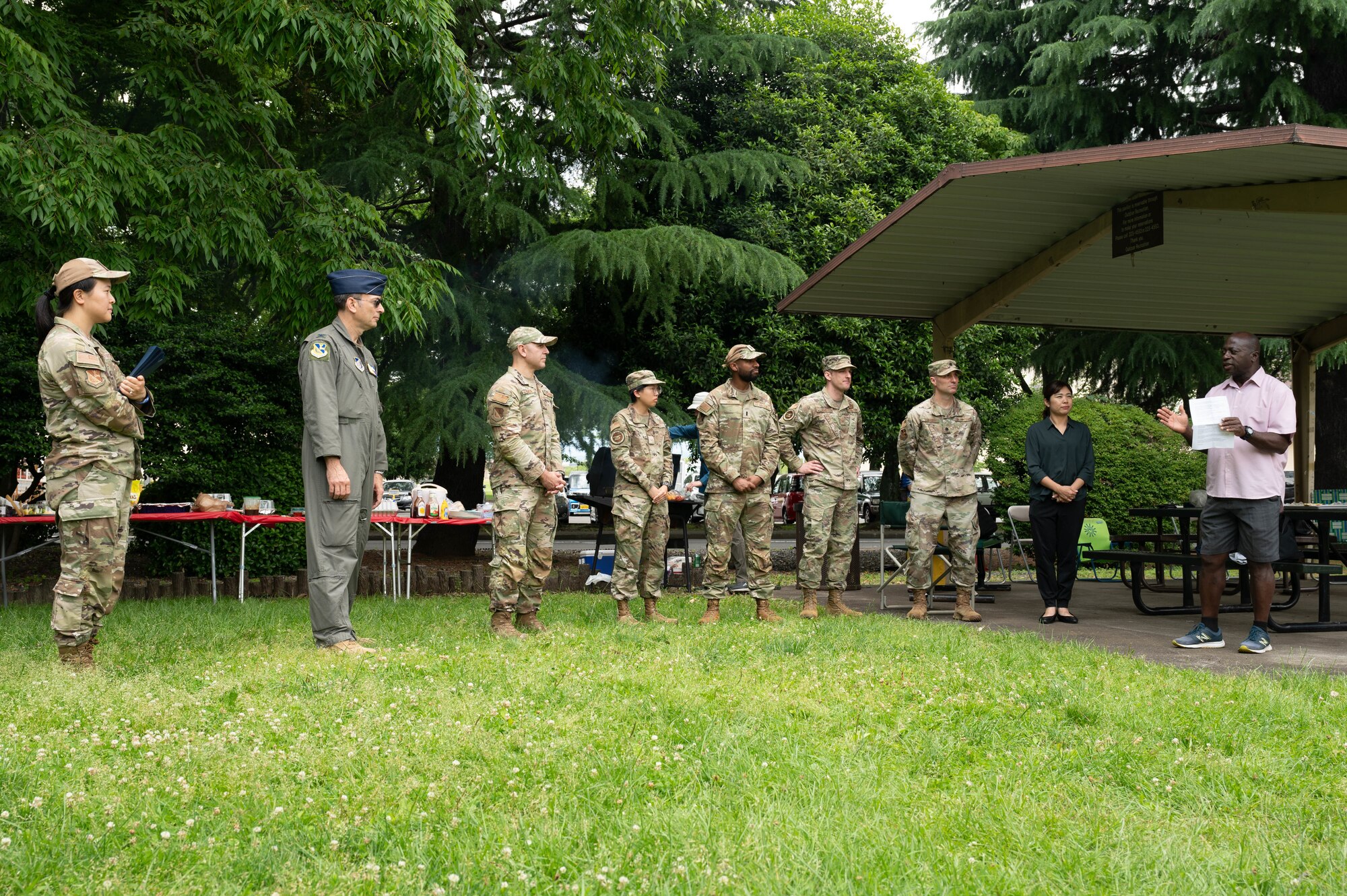 A group of people and servicemen stand in half circle.